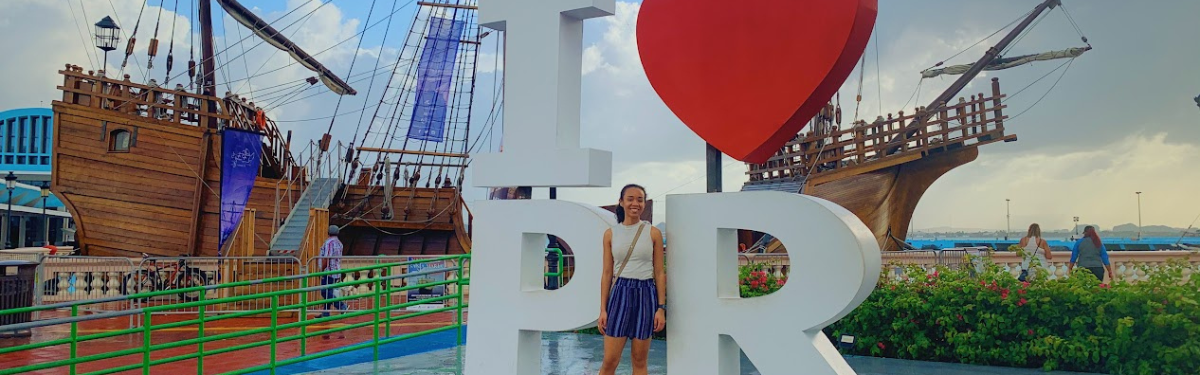 NSE student posing in front of the I heart puerto rico sign with ship in the background